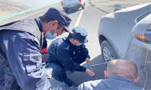 游客车胎扎了钉 民警前来帮换胎