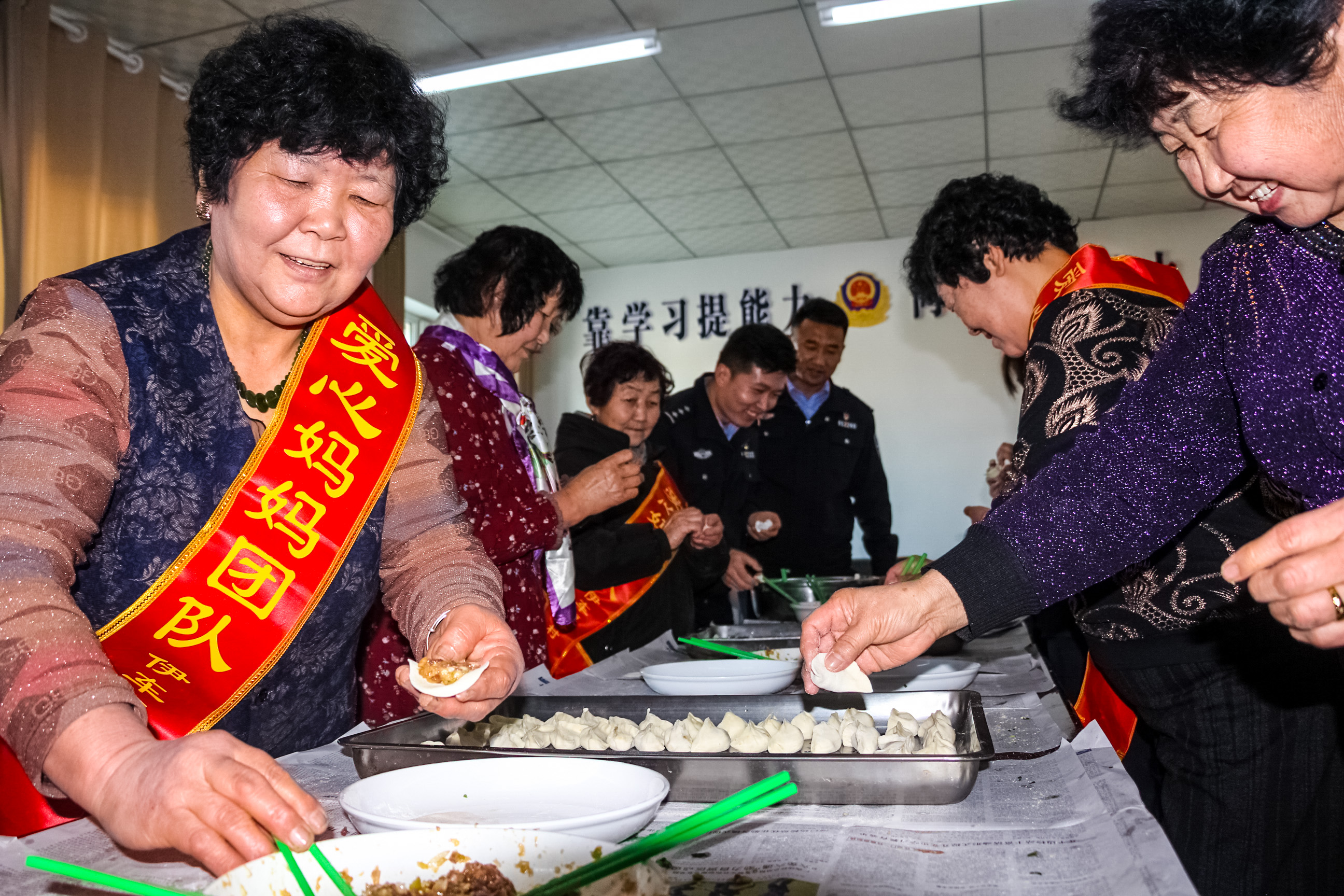 图四、2021年12月19日，图为“爱心妈妈”服务队成员与民辅警正在认真的包着饺子。.jpg