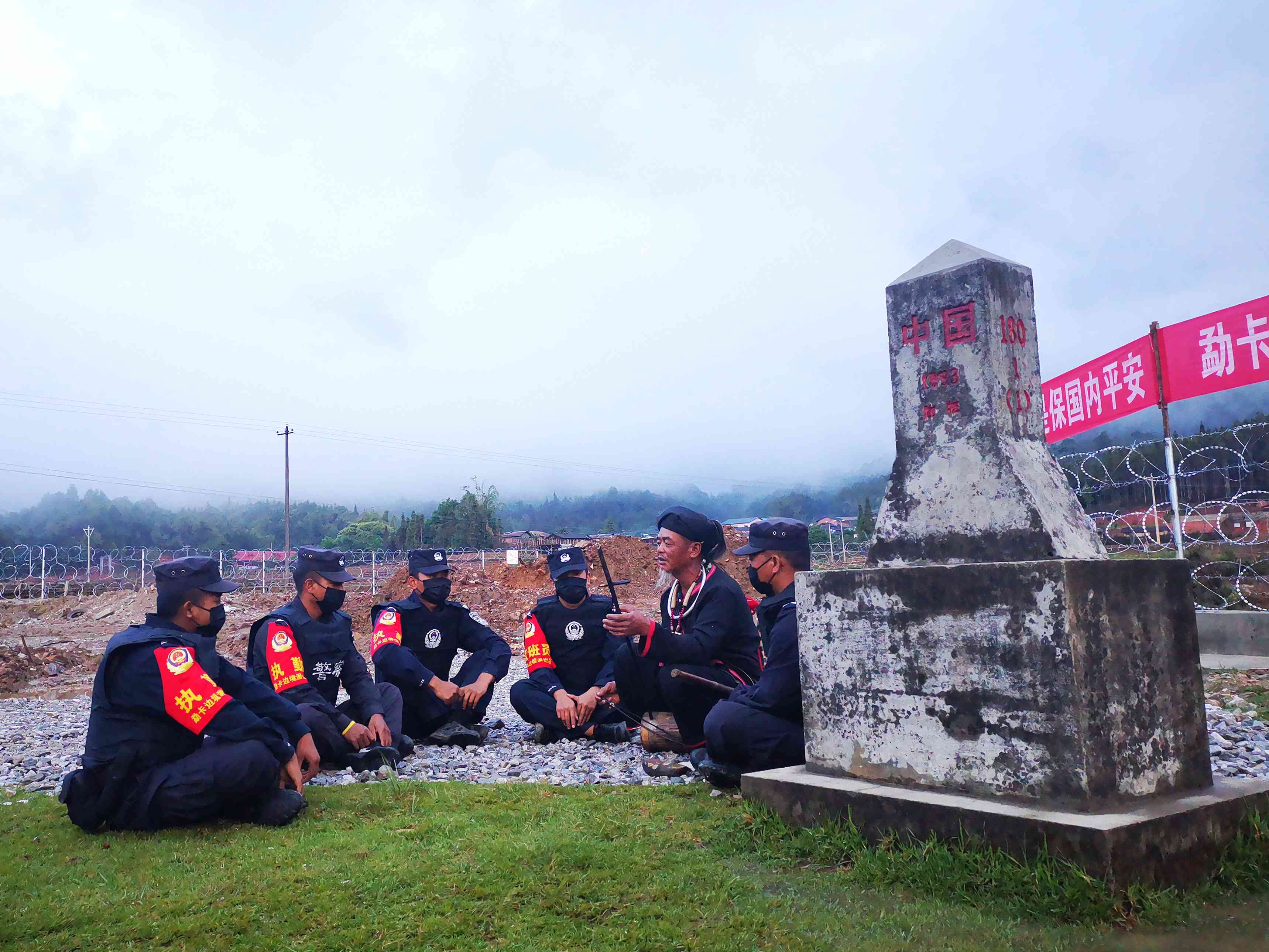 8.岩聪在中缅180附1号界桩处为民辅警演奏佤族传统乐器.jpg 8.岩聪在中缅180附1号界桩处为民辅警演奏佤族传统乐器.jpg