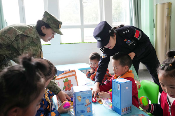 图为戍边民警与驻地部队官兵为庞达村双语幼儿园小朋友发放学习用品---摄影李锦辉.jpg