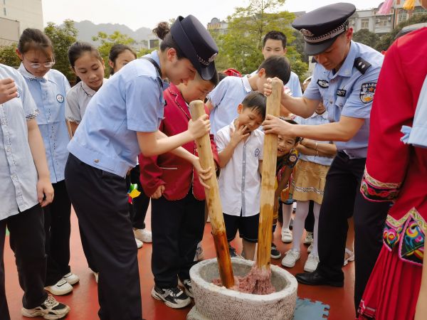 图为友谊关边检站移民管理警察为小朋友们舂糍粑（摄影 罗晓）.jpg