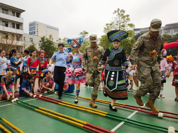 图为友谊关边检站移民管理警察与少数民族边民及驻地部队一起跳壮族竹竿舞（摄影 王皓东）.jpg