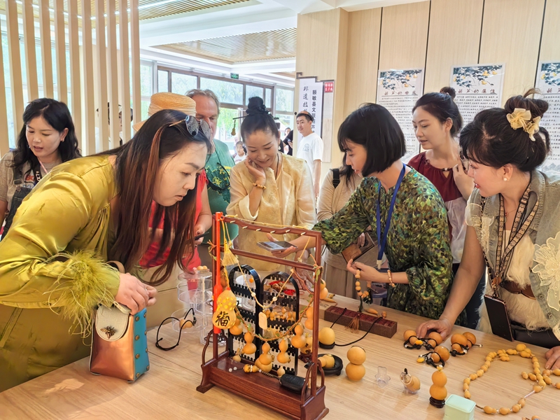 中外游客在额新疆塔城敏县榆柳巷选购葫芦烙画文创产品.jpg