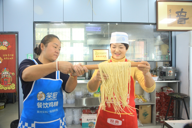 六师新湖农场百年碱香豚子面馆个体商户王娟(右)向乌鲁木齐市、六师五家渠市网络达人展示臊子面的制作全过程  魏新江摄.jpg